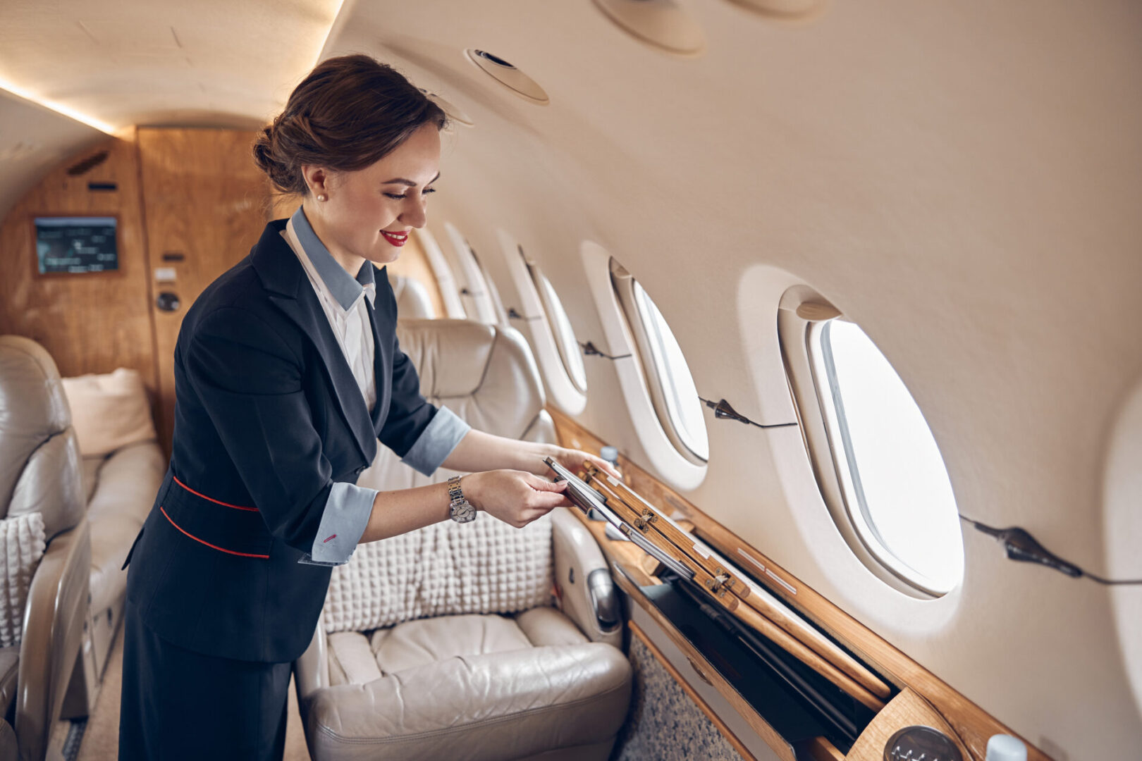 Flight attendant preparing luxury private jet cabin.